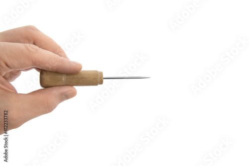 fingers hand holds a construction tool - awl; sewing tool photo