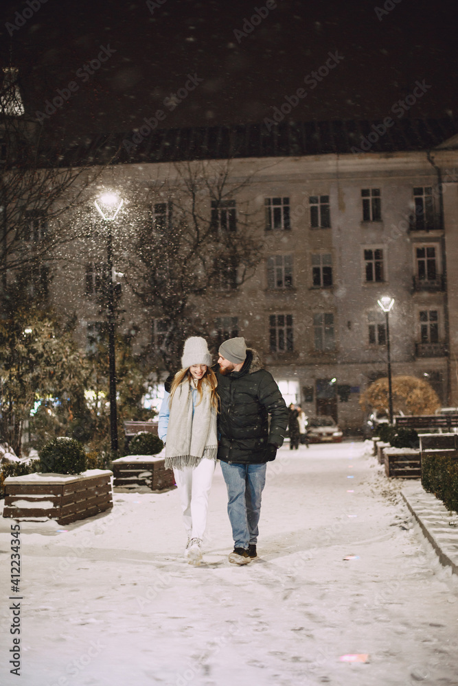 Winter holidays conception. Outdoor night portrait of young couple. Posing in street of European city.