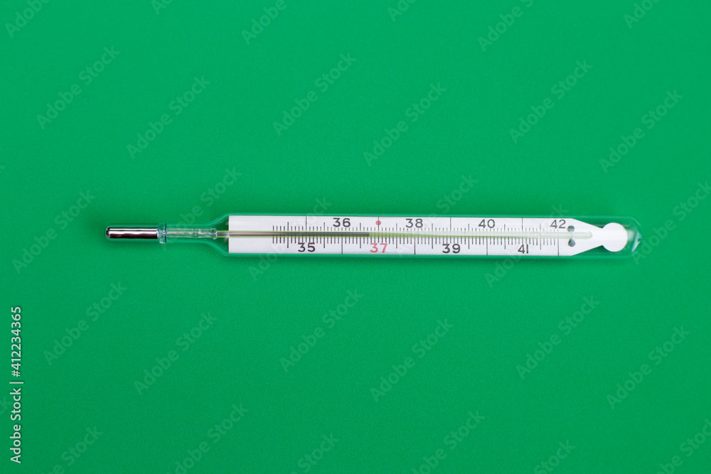 A thermometer with mercury on a green background. A medical device for measuring temperature. A thermometer with mercury on a green background. A medical device for measuring temperature.