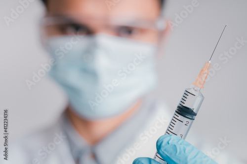 Doctors wear a surgical mask and glasses, Scientists, Scientists hold syringes and vaccines for COVID-19., vaccination and laboratory experiments. Virus protection concept COVID-19,