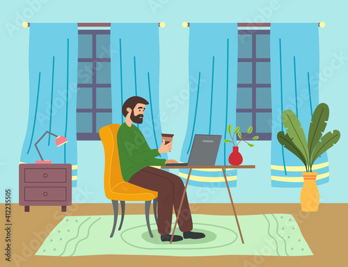 Bearded man with coffee sitting at table in room and correspondence surfing the Internet. Male character communicating through network on the laptop. Freelance, work from home and home office concept