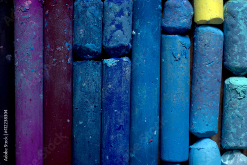 Background of many multicolored oil pastel crayons, top view.
Used colorful pastel chalks in geometrical order. Artist supplies and accessories. Abstract horizontal background. Rainbow colors. 