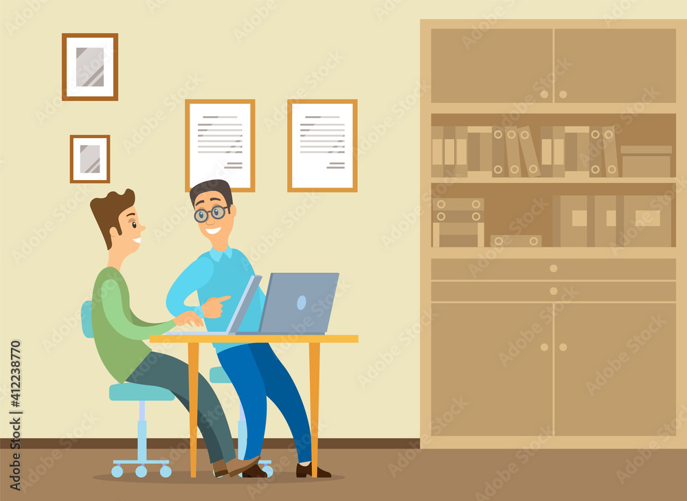 Young man is sitting at a desk with laptop, his colleague is pointing to a screen and giving advice. Office workers discussing work moments. Business meeting and communication. Friendly team work Young man is sitting at a desk with laptop, his colleague is pointing to a screen and giving advice. Office workers discussing work moments. Business meeting and communication. Friendly team work