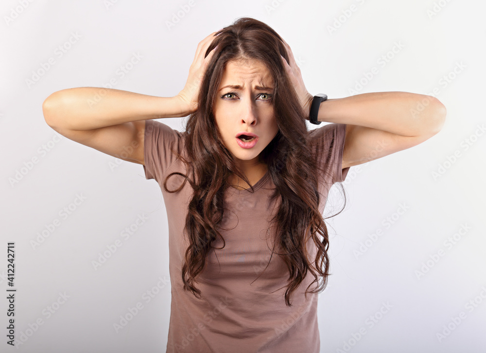 Fototapeta premium Angry young surprising business woman holding the head the hands with big eyes. Fun humor casual portrait