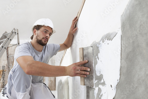 Foto Hands man plasterer construction worker at work with trowel, plastering a wall,