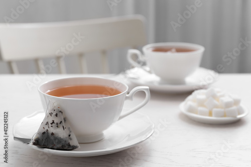Tea bag and cup of hot drink on white wooden table. Space for text