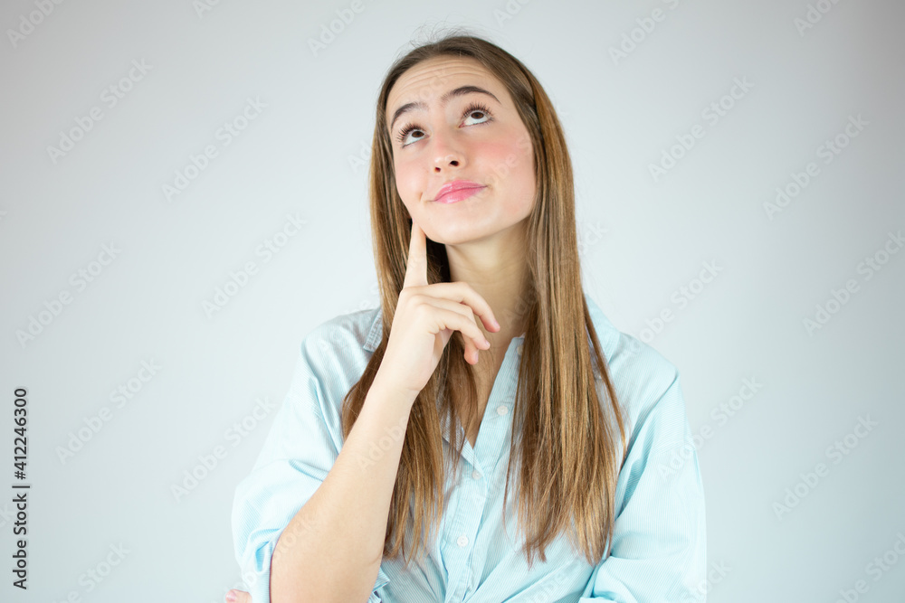 Young woman over isolated white background thinking an idea while looking up Young woman over isolated white background thinking an idea while looking up