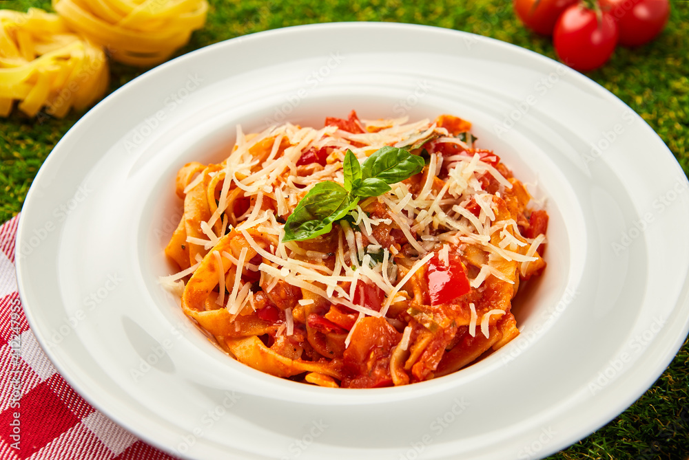 Classic italian pasta arrabiata with basil and freshly parmesan cheese on a green grass background Classic italian pasta arrabiata with basil and freshly parmesan cheese on a green grass background