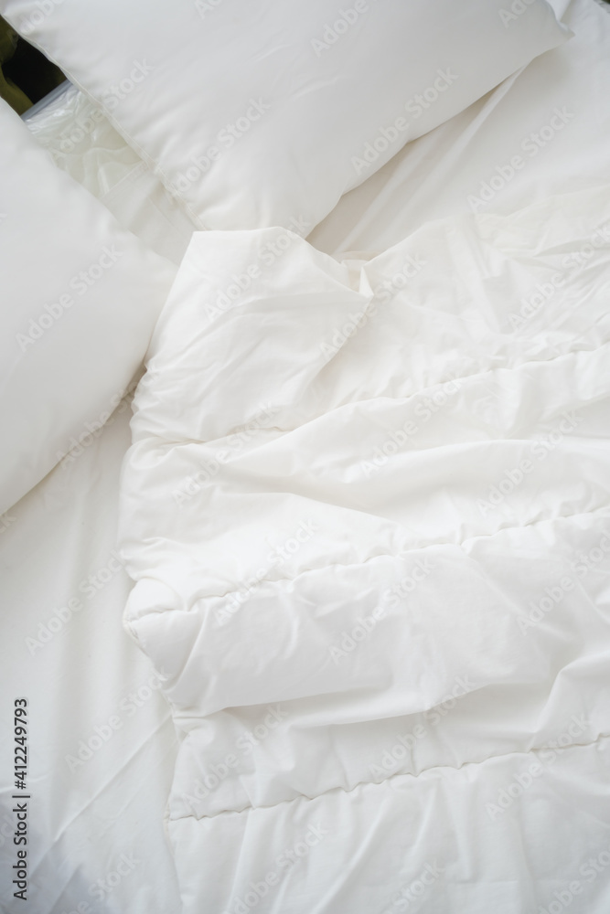 Soft white pillows on messy bed, closeup.