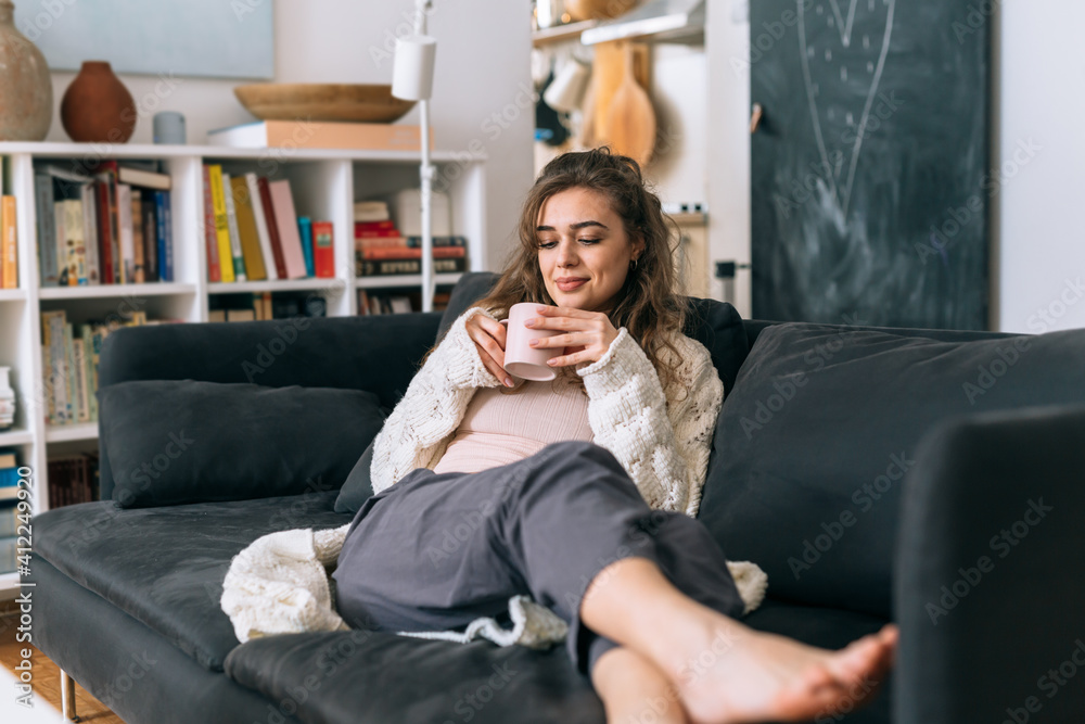 young woman relaxing on sofa while drinking morning coffee young woman relaxing on sofa while drinking morning coffee