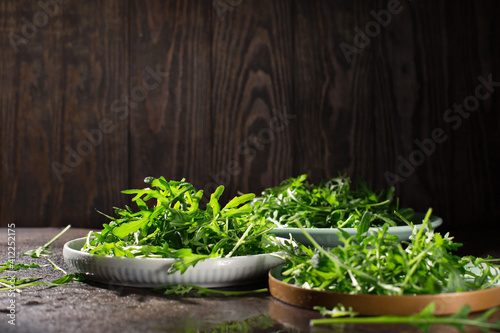 Fresh green raw leaves of arugula rucola salad on dark rustic wooden background.