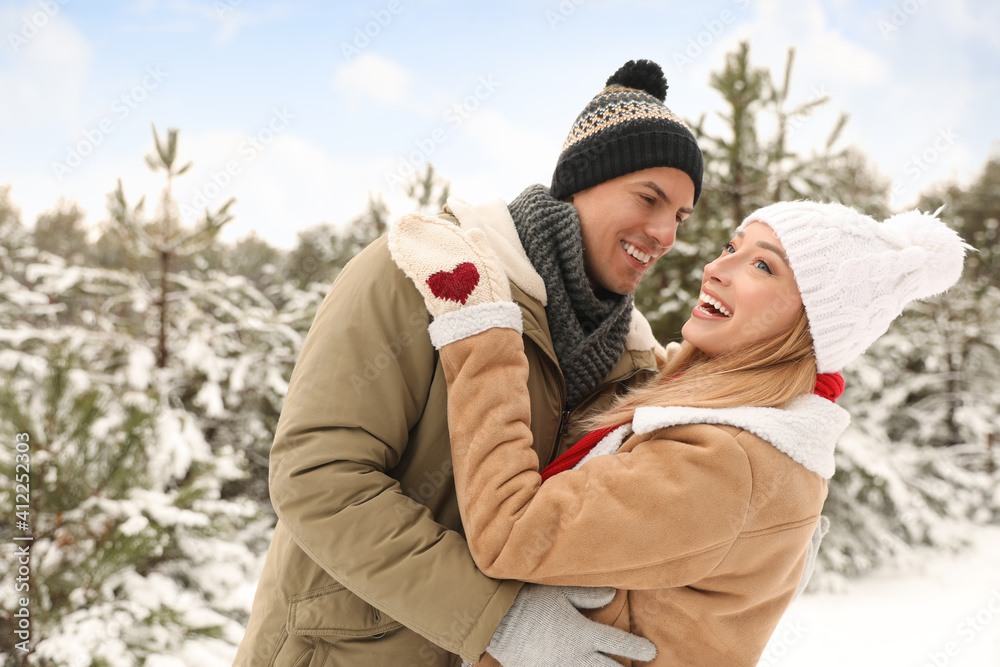 Beautiful happy couple in snowy forest on winter day Beautiful happy couple in snowy forest on winter day