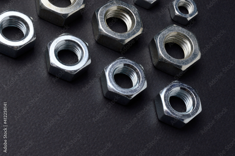 new chrome nuts of different sizes are laid out against a dark background. close-up. new chrome nuts of different sizes are laid out against a dark background. close-up.