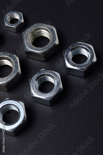 new chrome nuts of different sizes are laid out against a dark background. close-up.