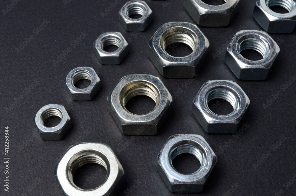 new chrome nuts of different sizes are laid out against a dark background. close-up. new chrome nuts of different sizes are laid out against a dark background. close-up.
