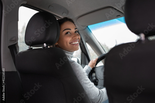 Young woman driving car, trip of business lady in sunny weather