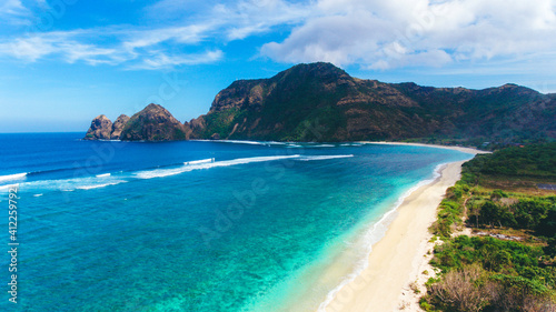 Long beatiful beach with white sands and blue sea water. Beautiful aerial view with long waves and a hill in Tropical Beach, West Sumbawa, Indonesia
