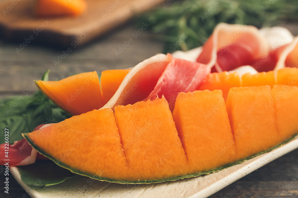 Plate with delicious melon and prosciutto on wooden background, closeup Plate with delicious melon and prosciutto on wooden background, closeup