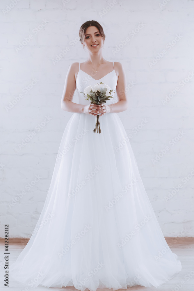 Beautiful happy sophisticated bride in a wedding dress in a light room Beautiful happy sophisticated bride in a wedding dress in a light room