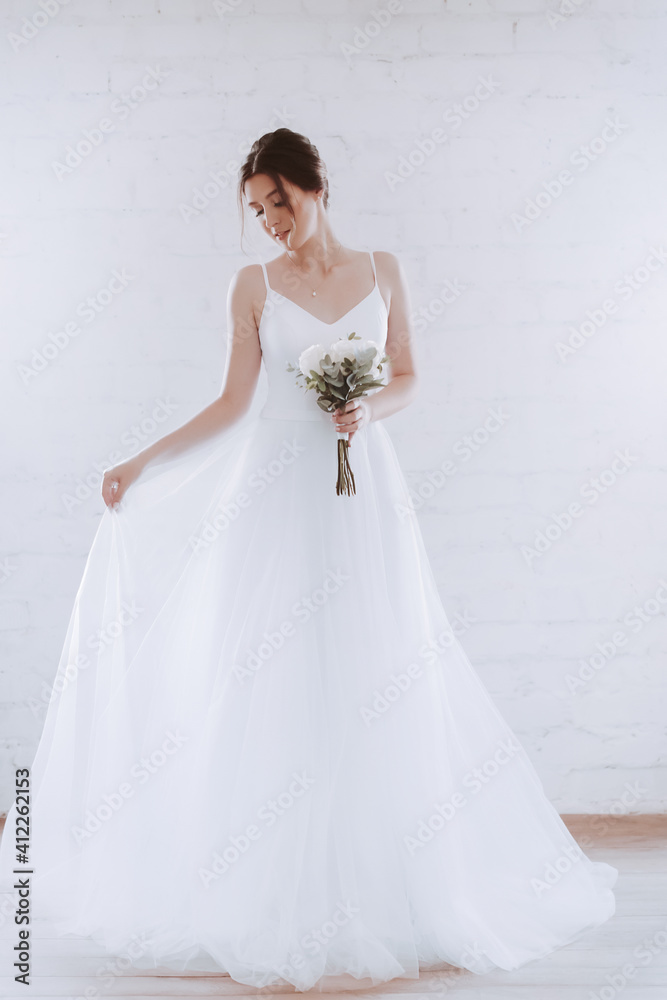 Beautiful happy sophisticated bride in a wedding dress in a light room Beautiful happy sophisticated bride in a wedding dress in a light room