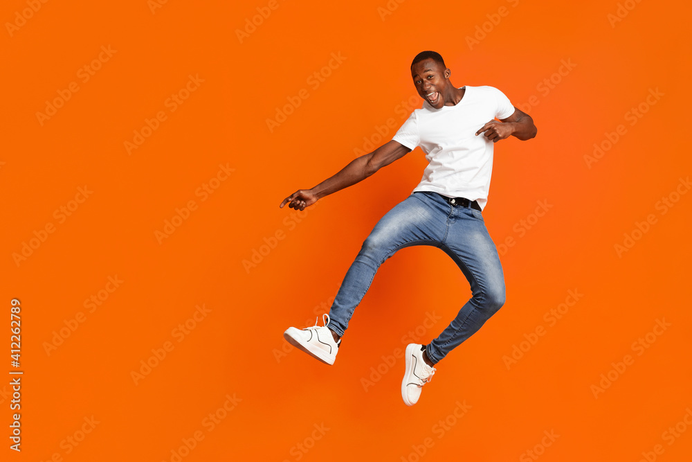 Positive black guy jumping up and showing copy space