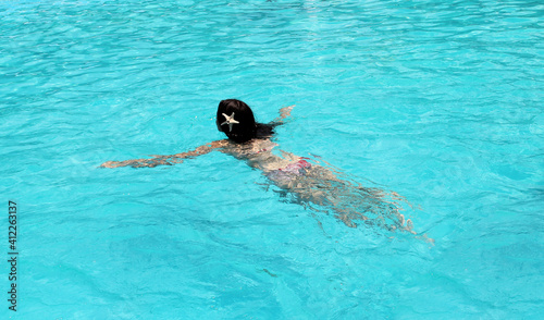 Beautiful young woman swimming and enjoying in swimming pool