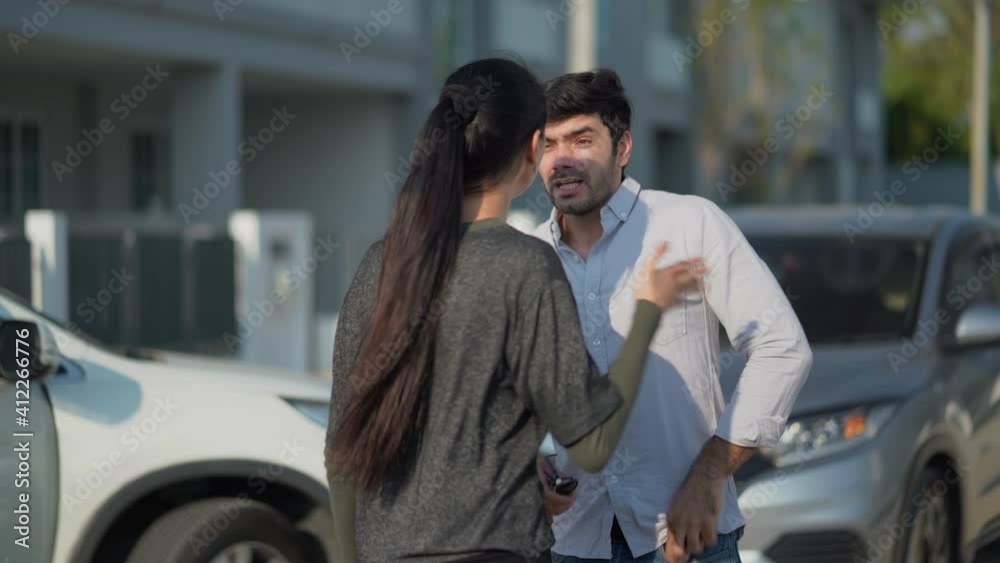 Two angry motorists arguing after a car accident on the road calling insurance company on mobile phone to responsibility for car accident traffic collision. furious driver man shouting to stress woman