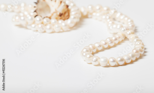 Close-up photo of natural pearls with sea shell on white.