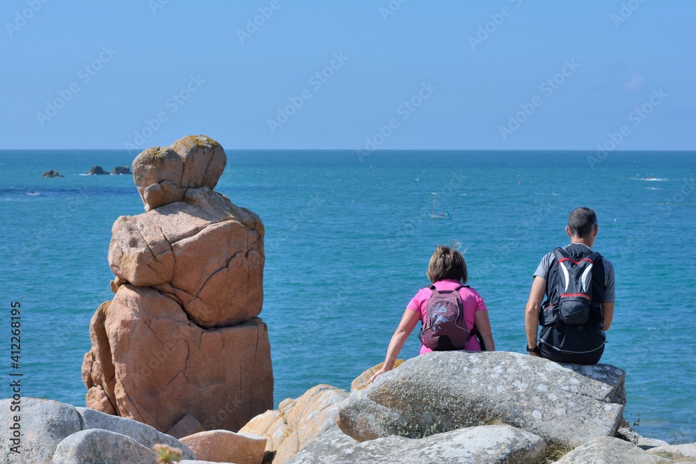 Couple of people and couple in rock in front of the sea in Brittany. France