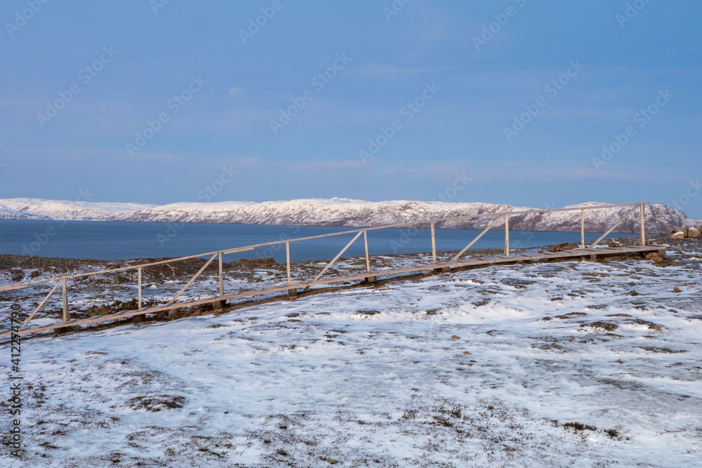 A wooden path through the snow-covered winter tundra.