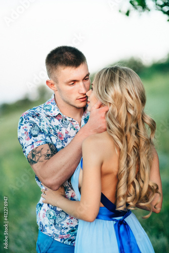 Cuadro en lienzo blonde girl with loose hair in a light blue dress and a guy in the light of suns