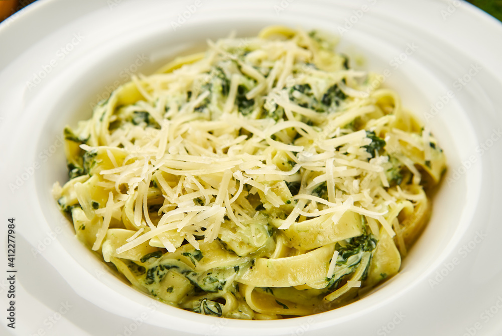 Traditional italian Pasta tagliatelli with spinach, hard parmesan cheese and cream sauce