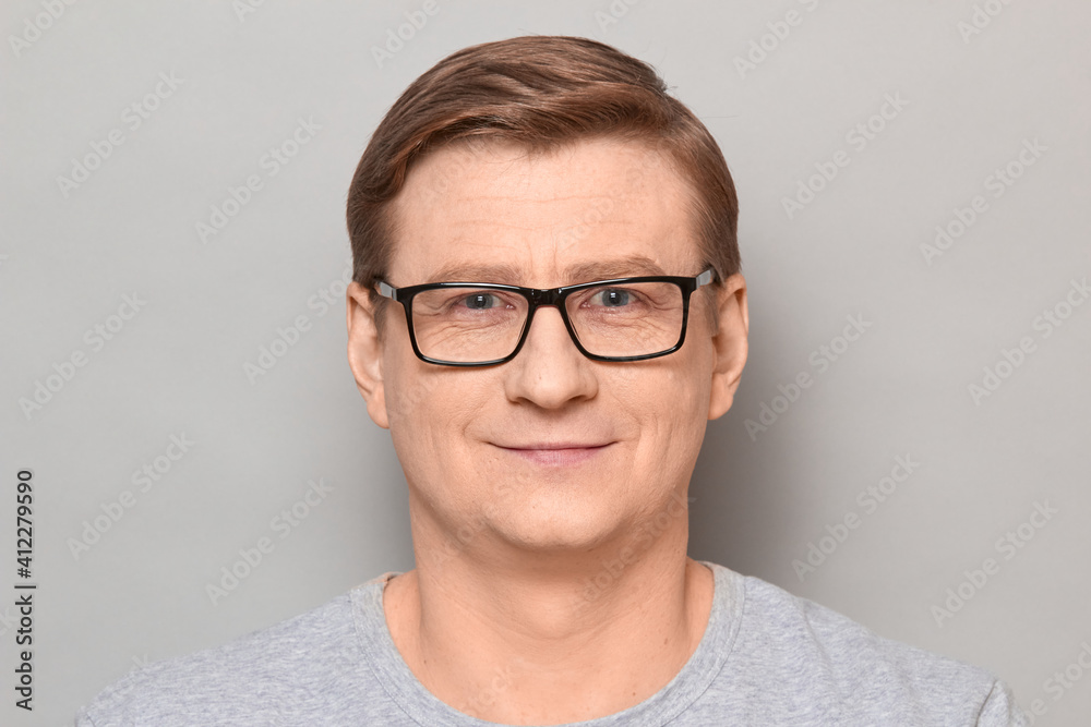 Portrait of happy blond mature man with glasses smiling cheerfully