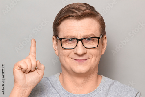Portrait of happy cheerful man raising index finger and smiling