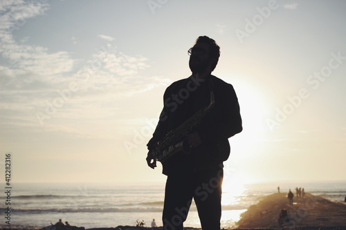 Backlit saxophone player in front of the ocean