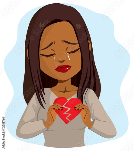 Beautiful young black woman crying sad while holding broken heart concept