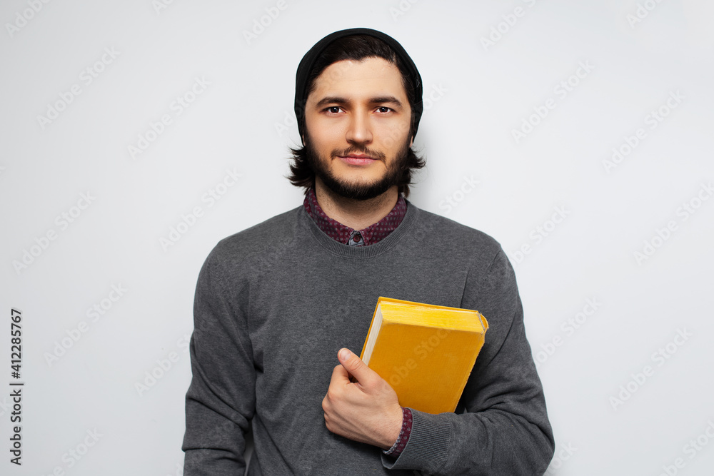 Studio portrait of young man holding a book on white background. Studio portrait of young man holding a book on white background.