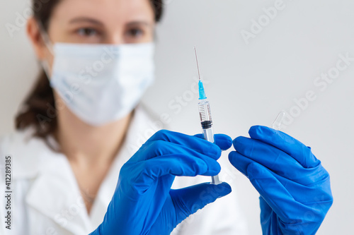 The concept of the new coronavirus COVID-19,2019-nCoV. Syringe with a vaccine in a doctor's hand, close-up.