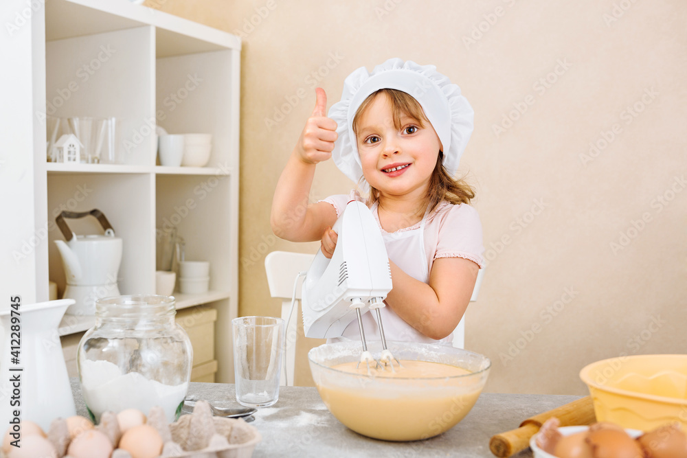 A cheerful young mother's assistant kneads the dough for a pie with a mixer, performs a step-by-step recipe on a tablet A cheerful young mother's assistant kneads the dough for a pie with a mixer, performs a step-by-step recipe on a tablet
