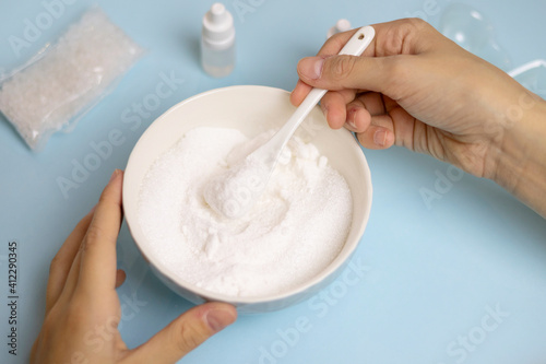 a child makes a bath bomb from sea salt, citric acid, soda, dye and flavor on a blue background, instructions, step 1