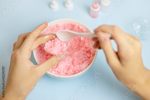 a child makes a bath bomb from sea salt, citric acid, soda, dye and flavor on a blue background, instructions, step 3