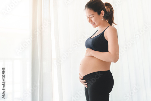 Young pregnant woman smiling and touching her belly, she holding baby in pregnant belly, Early pregnancy, Maternity prenatal care and woman pregnancy concept. Free Download Young pregnant woman smiling and touching her belly, she holding baby in pregnant belly, Early pregnancy, Maternity prenatal care and woman pregnancy concept. - GFXLoad