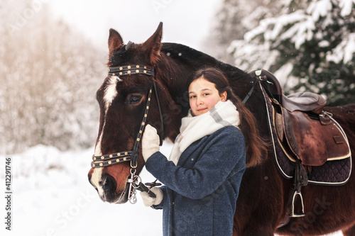 Young girl with a horse in winter in the woods. Communicating with nature and animals
