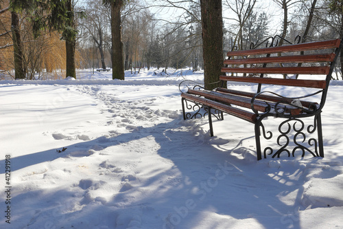 Empty bench in the winter city park, covered with snow. Snow covered the trees. Winter landscape.