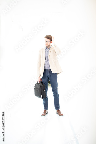 Confused businessman with a briefcase nestled in a blank white space. Strong backlight that he creates a muffled atmosphere. High key image