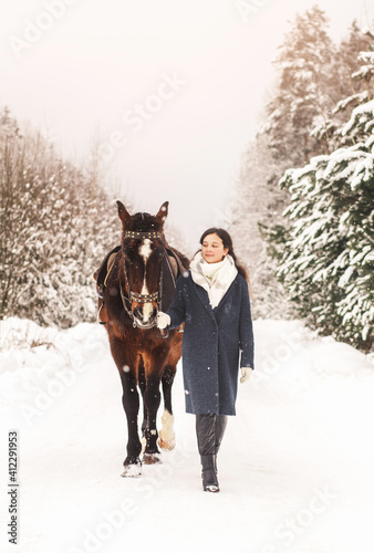 Young cute girl takes a walk horse in winter in nature. Human-animal friendship