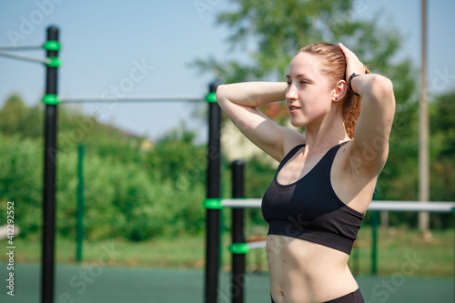 Sporty slim brunette woman dressed in cropped top and leggings does warm up before morning run pose outdoor wants to have slim body and good health. Workout, lifestyle