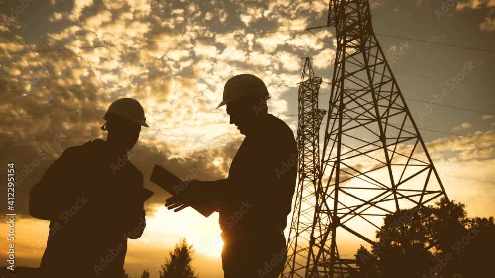 silhouette of an electricians engineers working next to an electrical support tower energy. electricity high teamwork tower sunset support. electricals engineers inspect teamwork electricity pylon