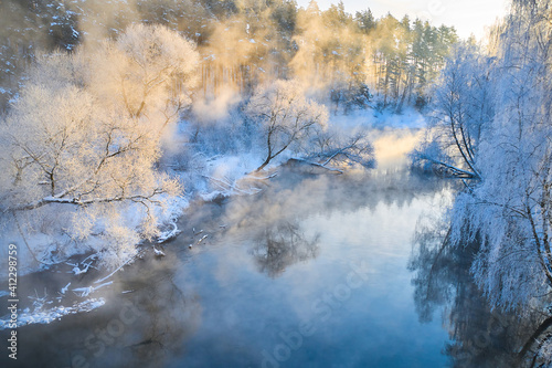 Beautiful morning landscape in winter. The river in the fog and the trees in the hoarfrost