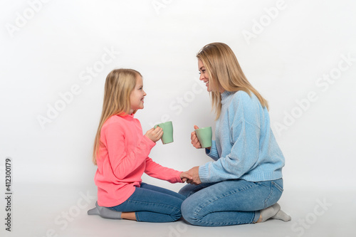 Young mother and daughter with cups of  tea  spends time together